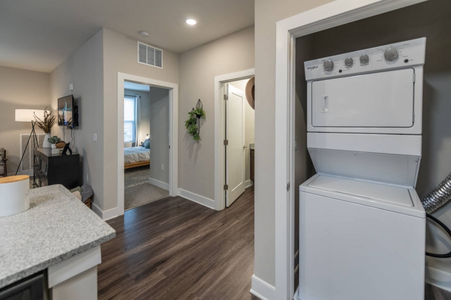 Attain at Harbour View luxury apartments with A stacked washer and dryer in a hallway closet of a modern apartment with wood flooring.