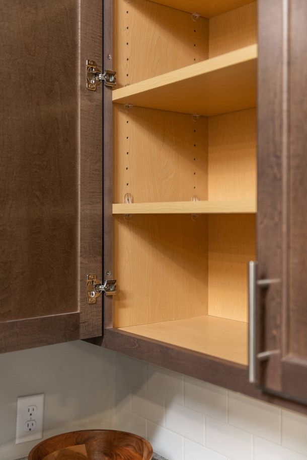 Attain at Harbour View luxury apartments with Open kitchen cabinet with empty wooden shelves and dark brown doors above a countertop.