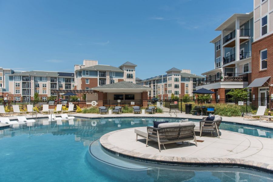 Attain at Harbour View luxury apartments with Outdoor pool with lounge chairs and seating area, surrounded by modern apartment buildings.