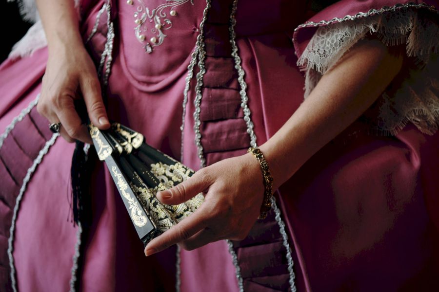 Attain at Harbour View luxury apartments with Person in a detailed pink historical dress holds an ornate black and gold fan with lace trim.