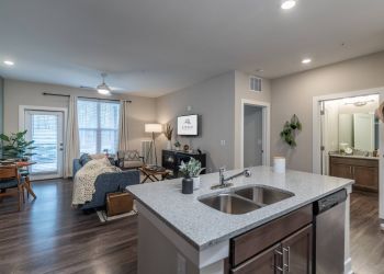 Attain at Harbour View luxury apartments with Modern open-plan apartment with kitchen island, living area, dining table, and TV, viewed from the kitchen.