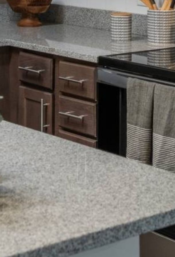 Attain at Harbour View luxury apartments with Granite kitchen countertops with dark wood cabinets and striped towels hanging on the oven door.