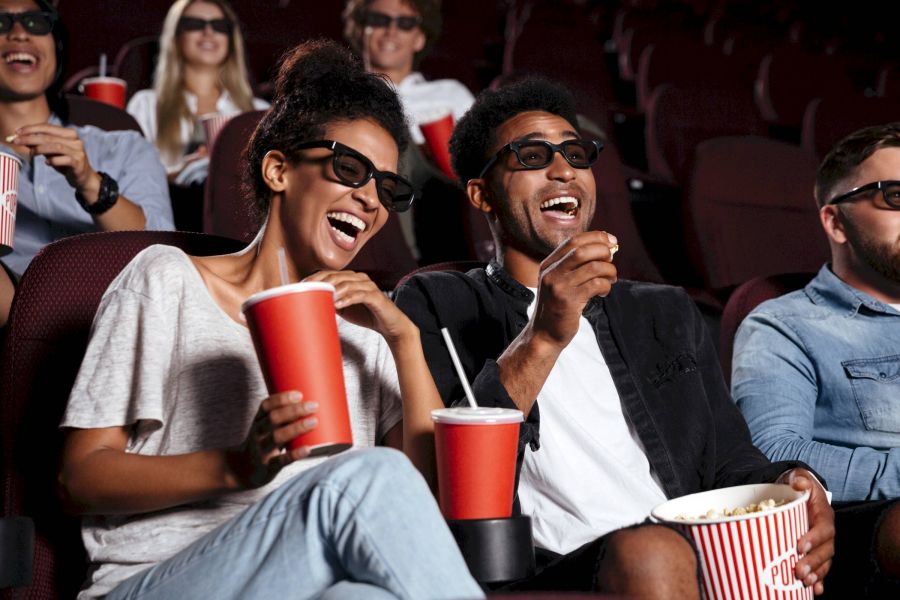 Attain at Harbour View luxury apartments with People wearing 3D glasses laughing and eating popcorn in a movie theater.