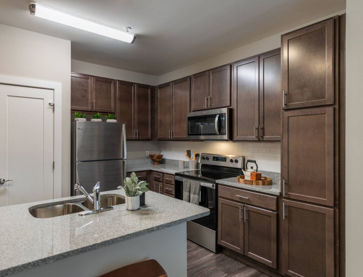 Attain at Harbour View luxury apartments with Modern kitchen with dark wood cabinets, stainless steel appliances, and a granite countertop island.