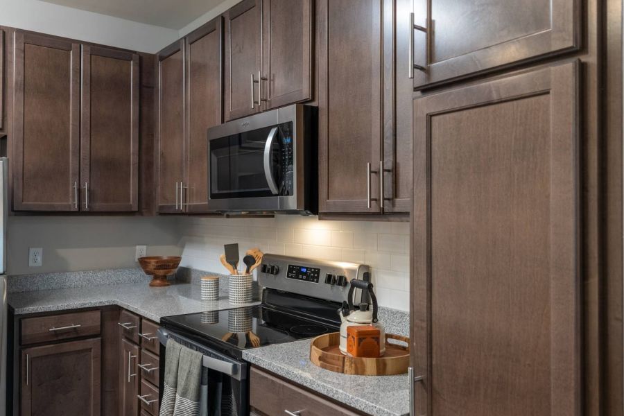 Attain at Harbour View luxury apartments with Modern kitchen with dark wood cabinets, stainless steel appliances, and light countertops.