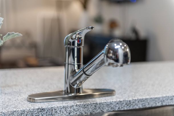 Attain at Harbour View luxury apartments with A modern chrome kitchen faucet with a pull-out sprayer on a speckled countertop.
